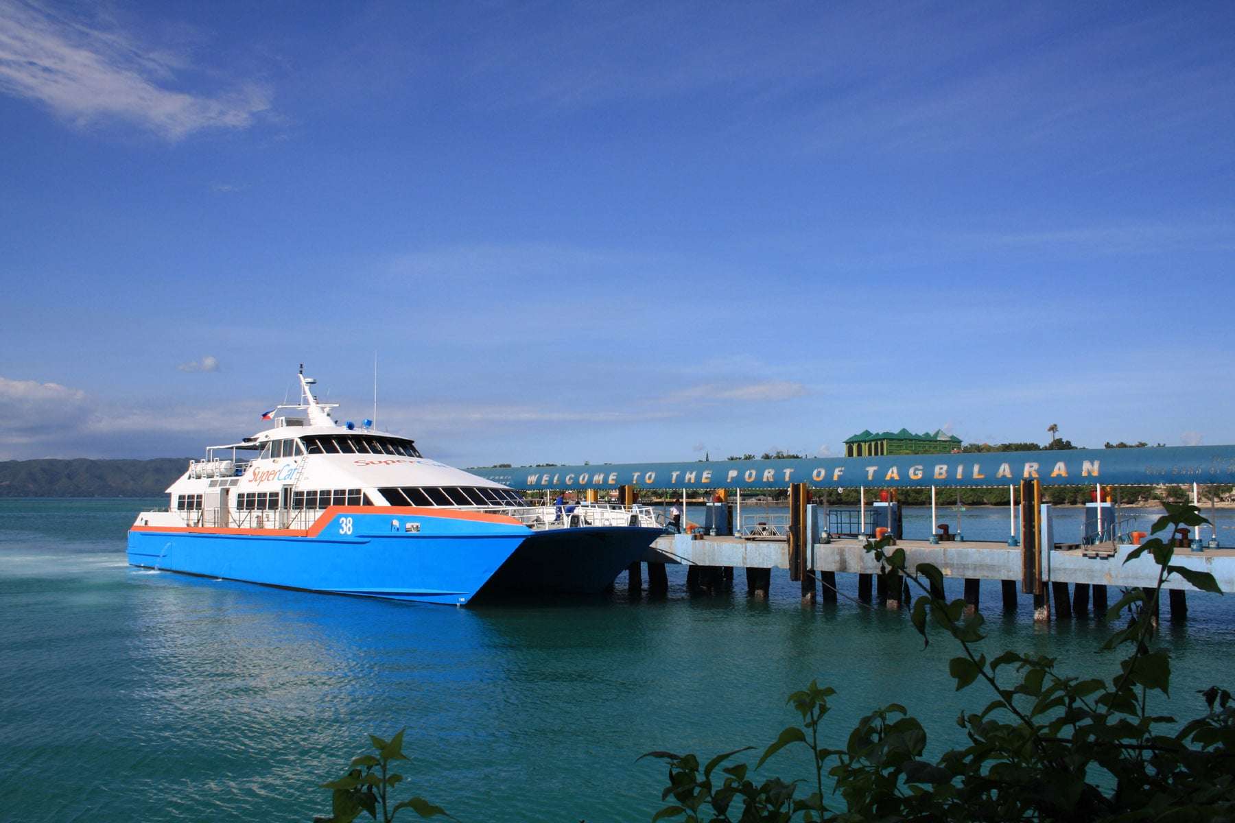 A SuperCat fast ferry docking under the Welcome to the Port of Tagbilaran sign in Bohol