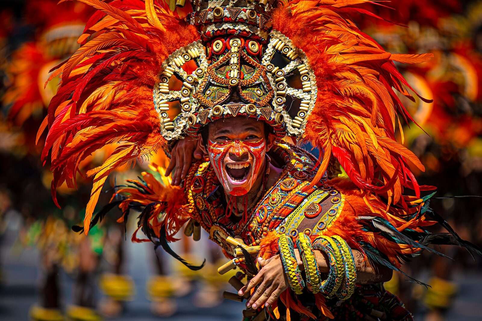 Dinagyang Festival Iloilo Ati tribe warrior performer in elaborate orange feathered headdress and traditional war paint at the annual January parade
