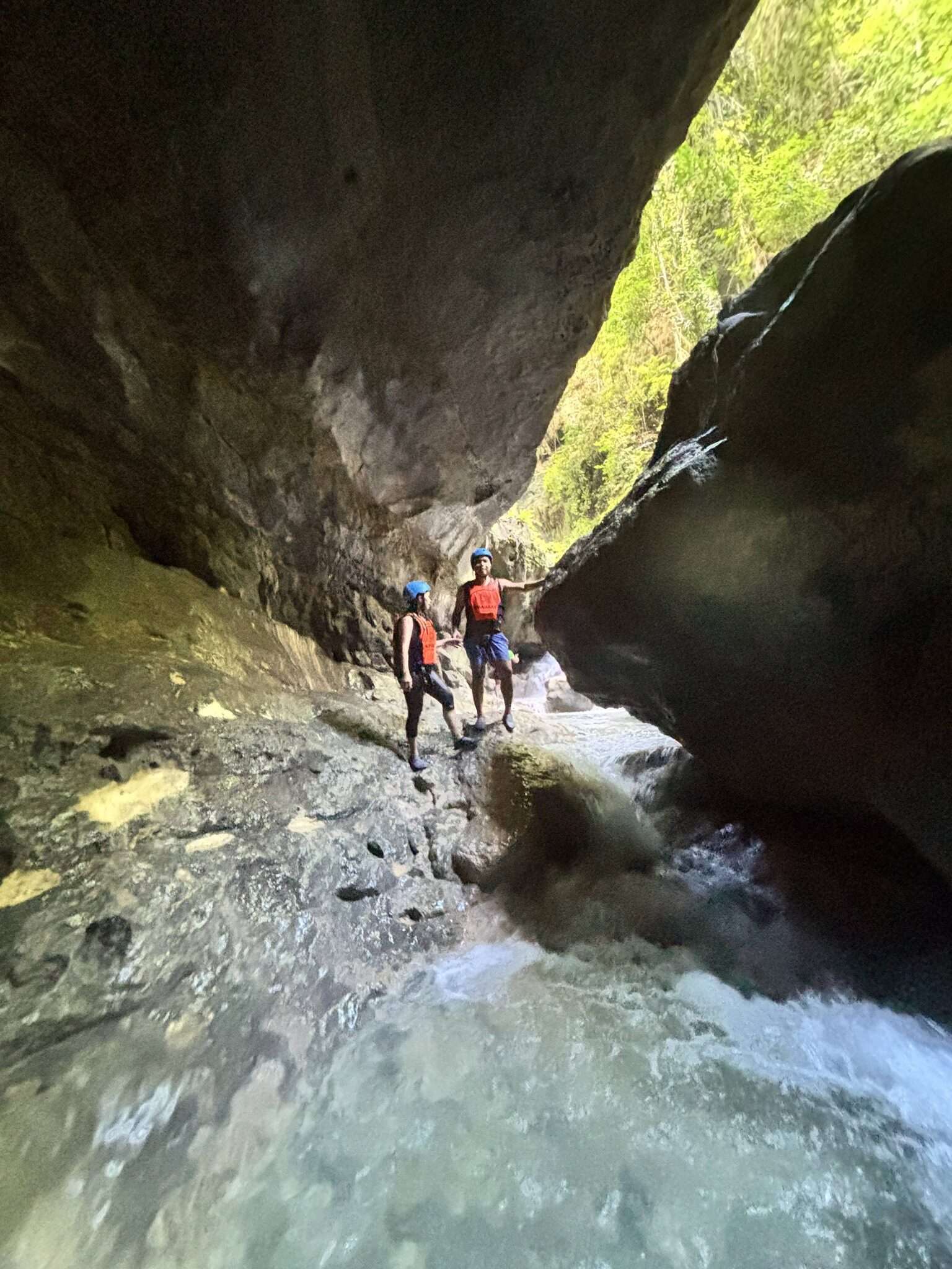 Kawasan Falls canyoneering Cebu two adventurers in helmets and life jackets standing on rocks in a narrow canyon stream