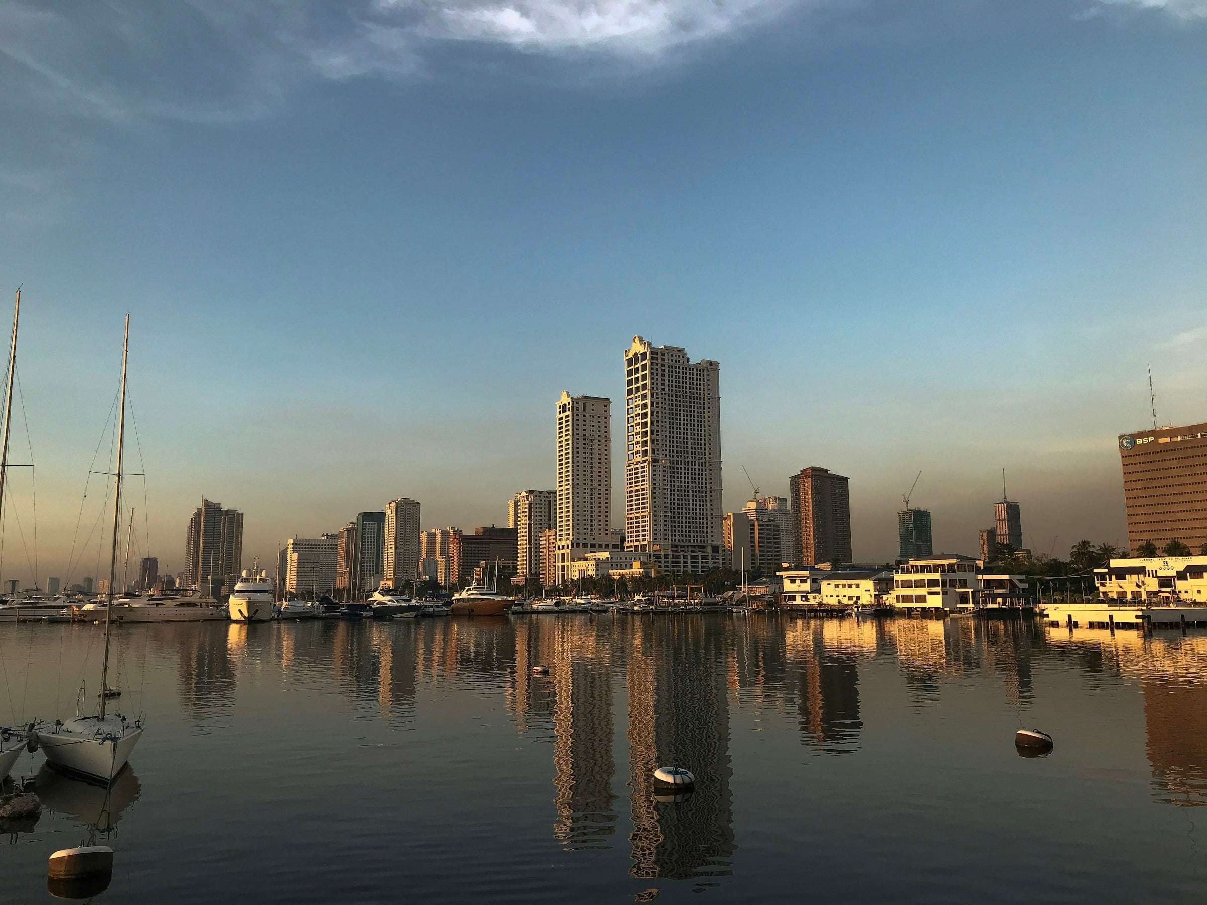 Photographers at Rizal Park Manila Luneta with the Rizal Monument obelisk and Philippine flag at sunset