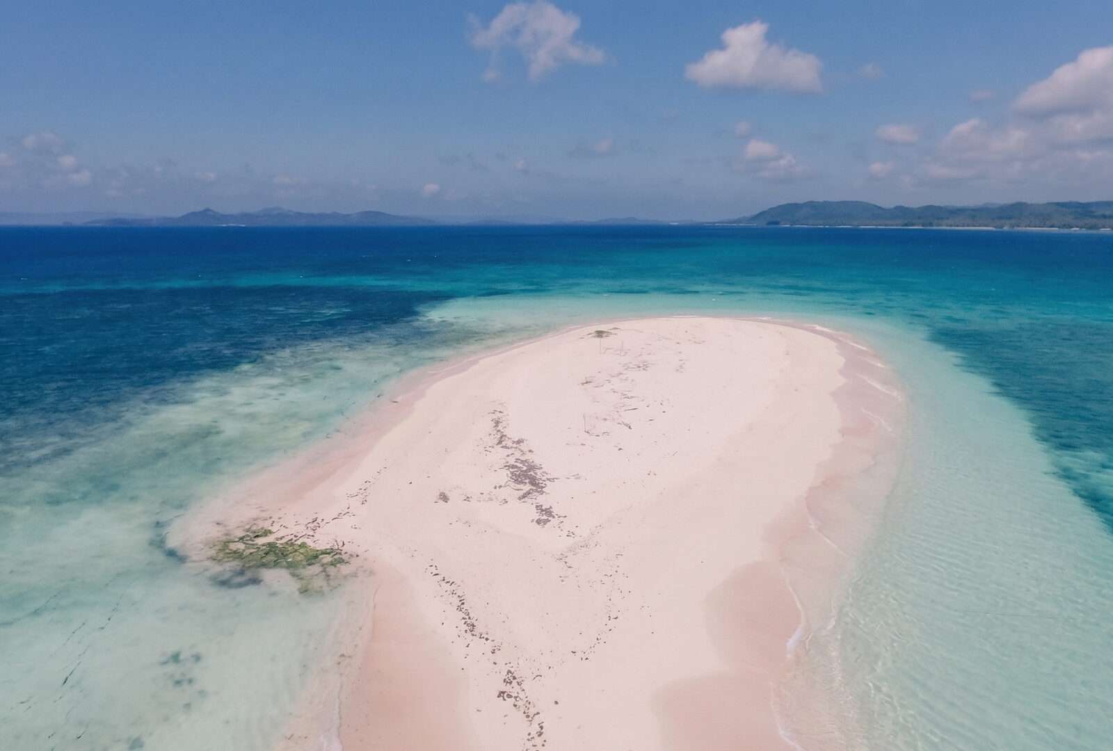 Aerial view of Naked Island Siargao long white sandbar with pink-tinged sand surrounded by turquoise ocean