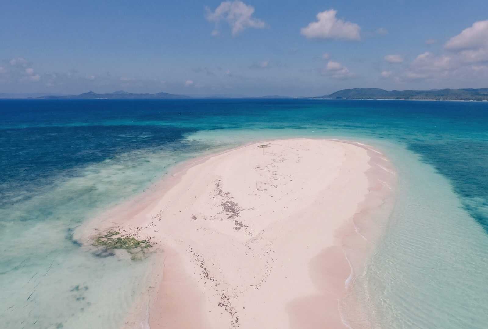 Aerial view of Naked Island Siargao long white sandbar with pink-tinged sand surrounded by turquoise ocean