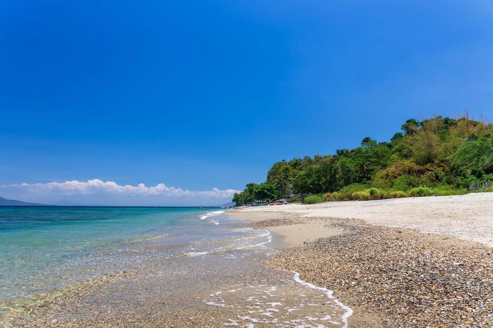 Aninuan Beach Puerto Galera quiet white sand beach with clear shallow water and green hillside, a peaceful alternative to White Beach in Mindoro