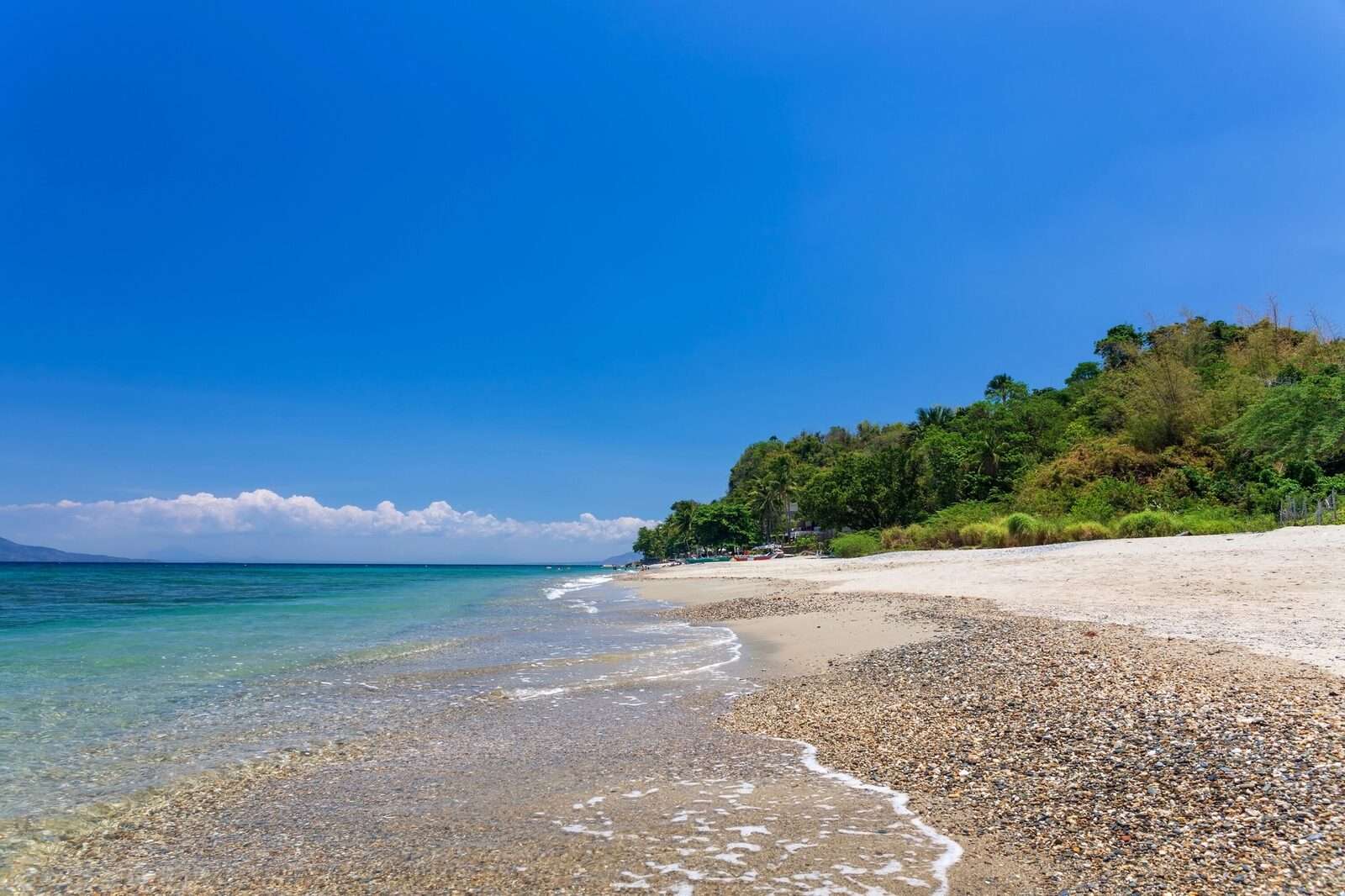Aninuan Beach Puerto Galera quiet white sand beach with clear shallow water and green hillside, a peaceful alternative to White Beach in Mindoro