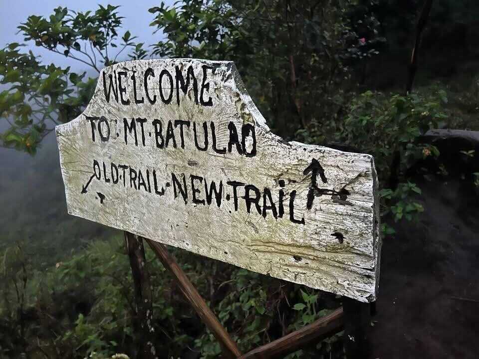 Mt. Batulao Batangas weathered wooden trail sign welcoming hikers with arrows pointing to Old Trail and New Trail at misty mountain trailhead
