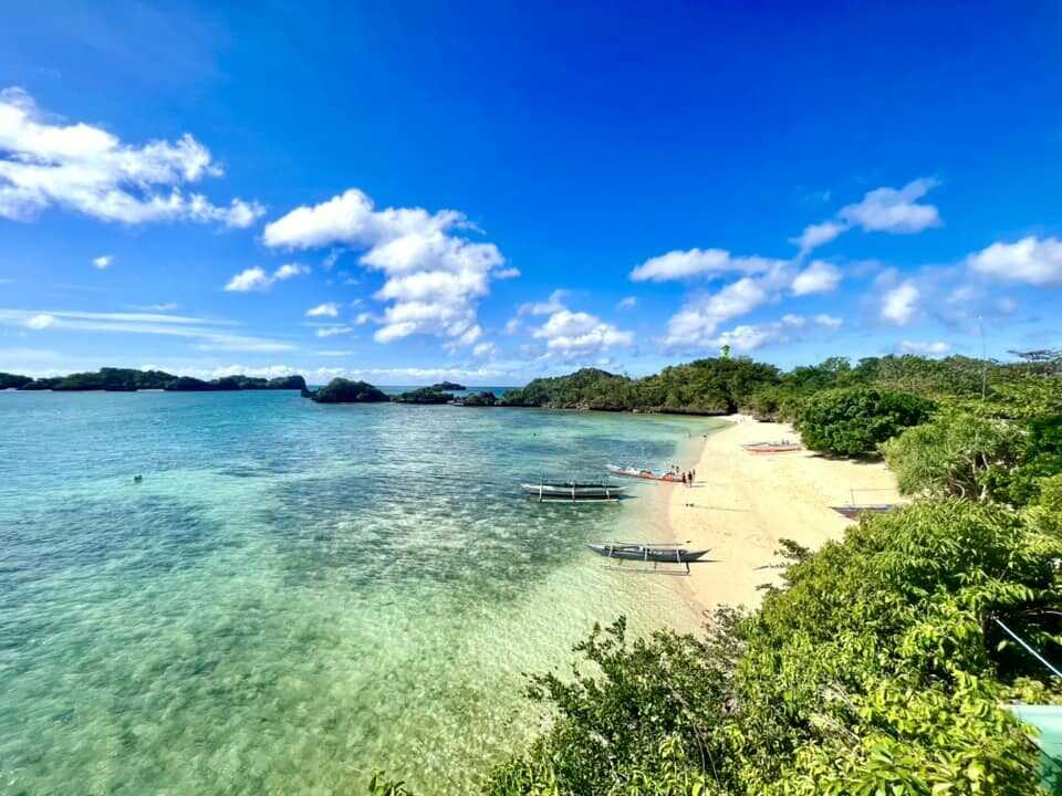 Guimaras Island day trip from Iloilo white sand cove with bangka outrigger boats turquoise water and tropical green islands in the distance